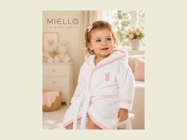 Toddler wearing a white hooded baby bathrobe with pink trim