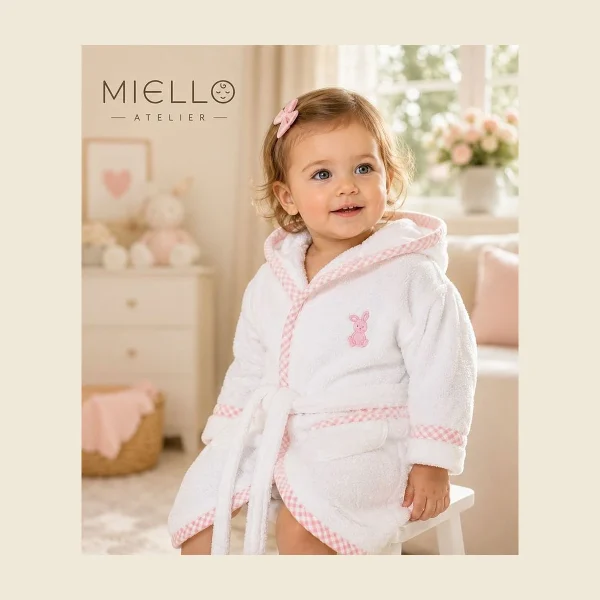 Toddler wearing a white hooded baby bathrobe with pink trim