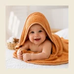 Baby wrapped in an orange hooded baby towel in soft Turkish cotton