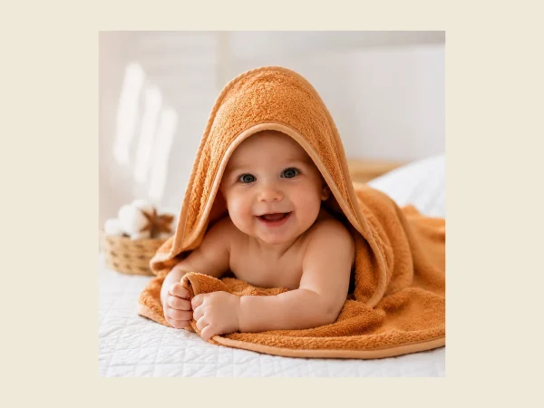 Baby wrapped in an orange hooded baby towel in soft Turkish cotton