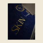 Navy towel with gold embroidered lettering shown close up on the embroidery machine