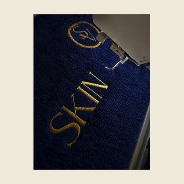 Navy towel with gold embroidered lettering shown close up on the embroidery machine