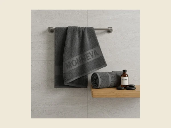 Jacquard terry towel with a MONNEVA motif woven into the looped pile hanging on a bathroom rail