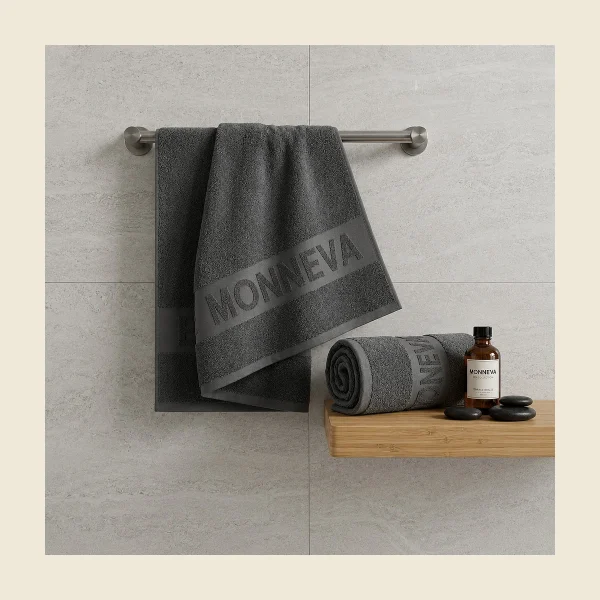 Jacquard terry towel with a MONNEVA motif woven into the looped pile hanging on a bathroom rail