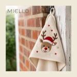 Child's hooded towel in cream with an embroidered reindeer motif hanging outdoors