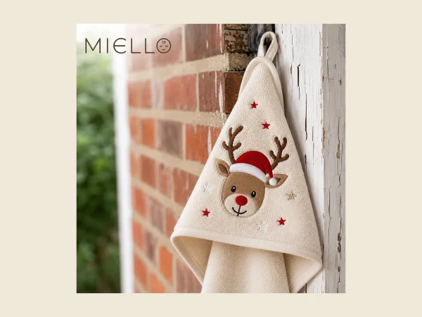 Child's hooded towel in cream with an embroidered reindeer motif hanging outdoors