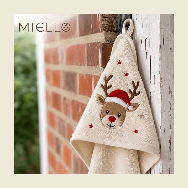 Child's hooded towel in cream with an embroidered reindeer motif hanging outdoors