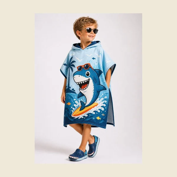 Child wearing a blue hooded kids beach poncho with a printed shark motif