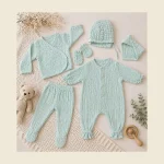 Newborn muslin set in mint laid out with wrap cardigan footed pants romper bonnet and mittens