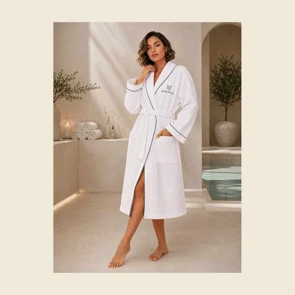 White hooded spa bathrobe with MONNEVA embroidery beside a wellness pool