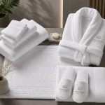 Complete hotel spa set with folded towels, embossed bath mat, bathrobe and slippers embroidered with a hotel logo